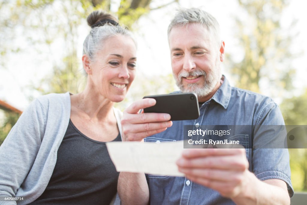 Couple d'âge mûr isolé avec téléphone bancaire