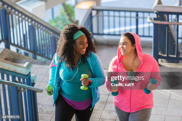 twee jonge vrouwen uit te oefenen, powerwalking omhoog trappen - plus size model stockfoto's en -beelden