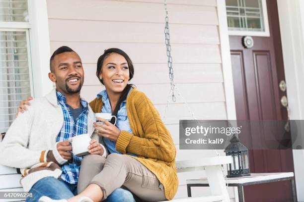 young mixte couple de race boire du café avec balançoire porche - loggia photos et images de collection