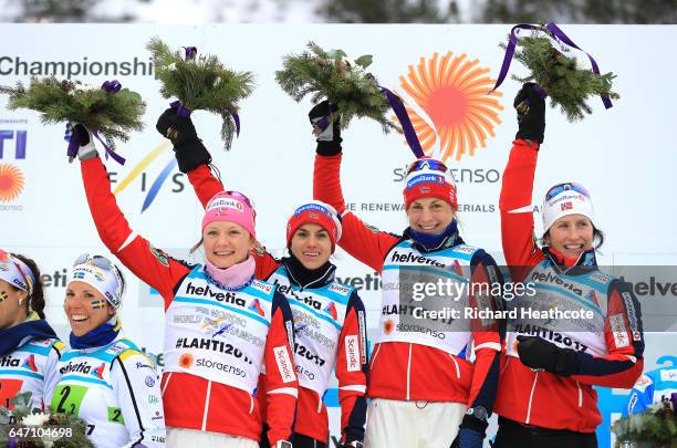 Gold medalists Maiken Caspersen Falla, Heidi Weng, Astrid Uhrenholdt Jacobsen and Marit Bjoergen of Norway celebrate during the flower ceremony for...