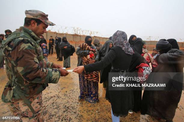 Member of the Jordanian security forces checks identification cards of Syrian refugees from the makeshift Rukban camp, which lies in no-man's-land...