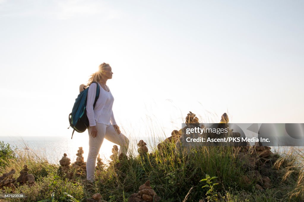 Woman pauses beside Zen rock piles, looks over sea