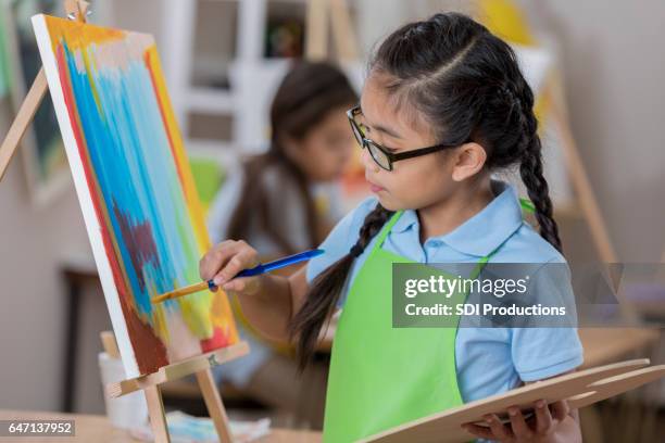 young artist concentrates while painting - easel stock pictures, royalty-free photos & images