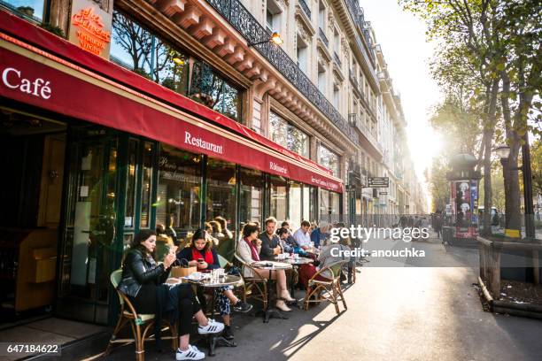 people relaxing, eating and drinking in restaurant in paris, france - patio restaurant stock pictures, royalty-free photos & images