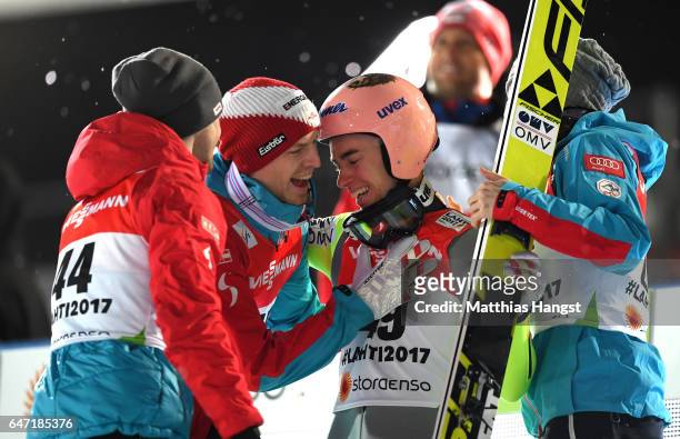 Stefan Kraft of Austria is congratulated by Michael Hayboeck of Austria and Manuel Fettner of Austria as he wins gold during the Men's Ski Jumping...