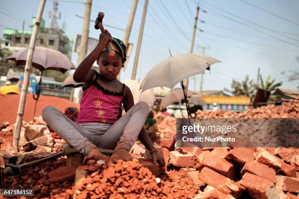 Child girl breaks brick beside the road in Narayanganj, Bangladesh on March 2, 2017.