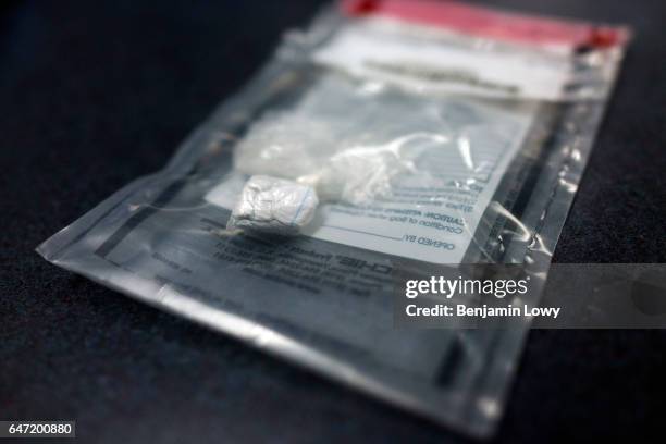 An East Liverpool police officer shows off an evidence bag filled with heroin. "We can't even touch these things anymore," he said "these drugs are...