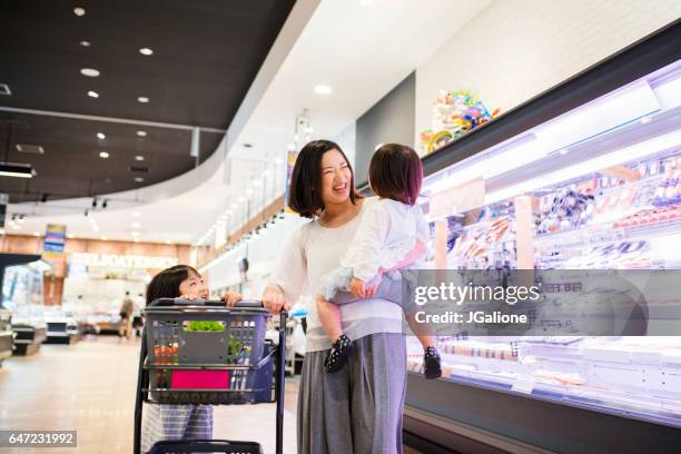 ragazza che aiuta sua madre spingendo il carrello della spesa - asian family shopping foto e immagini stock