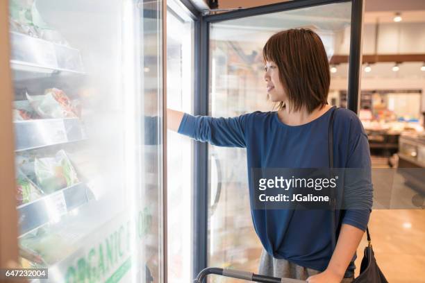 mujer joven, compra alimentos congelados - frozen food fotografías e imágenes de stock