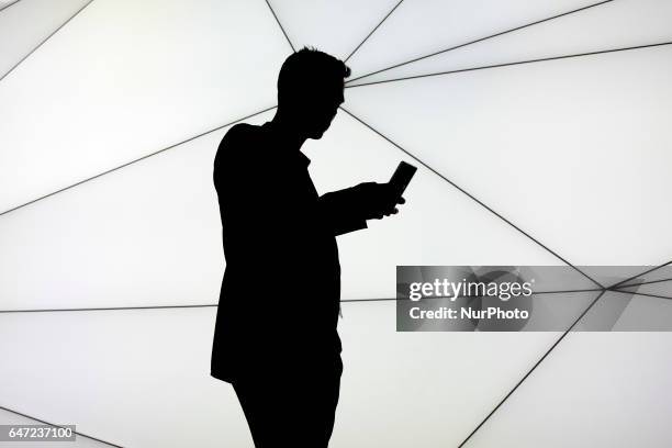 Backlighting of man using her smartphone between the february 27 and the march 2 during the Mobile World Congress in Barcelona, Spain