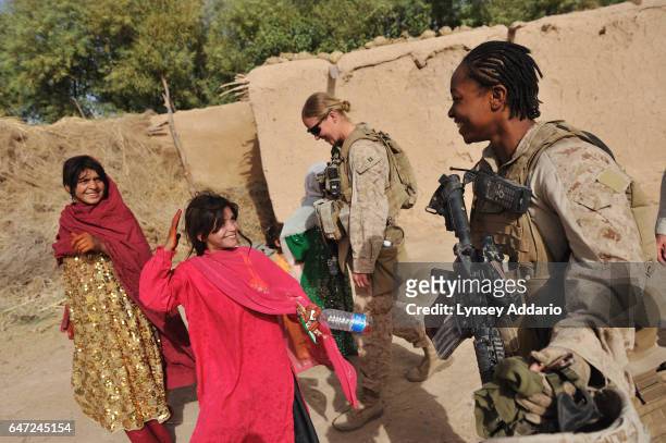United States Marines, Cpl. Christina Oliver right, takes off her helmet to show she is a female as a Female Engagement Team is invited by an Afghan...