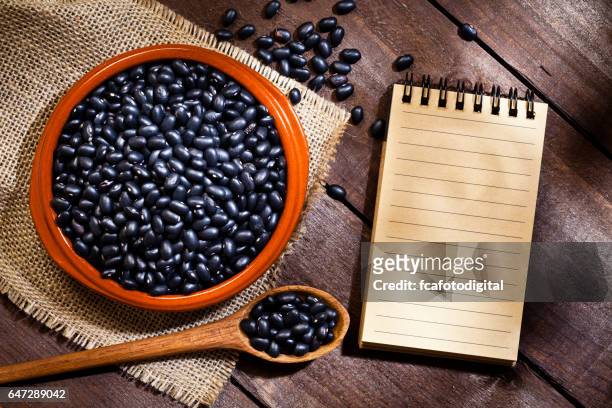 black beans in a bowl and blank cookbook - black beans stock pictures, royalty-free photos & images