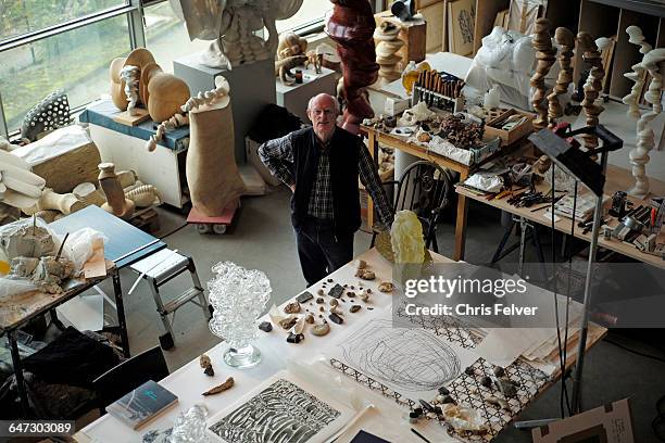 Elevated view of British artist Tony Cragg as he stands with some of his sculptures and other works in his studio, Wuppertal, Germany, April 2016.