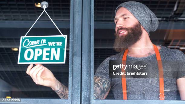 baard en getatoeëerd hipster openen de koffieshop - store sign stockfoto's en -beelden