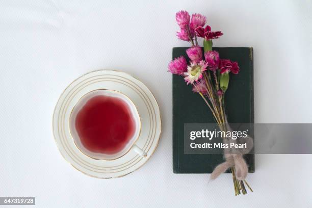 berry tea with wild flowers and old book - tea cup stock-fotos und bilder