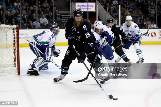 Joe Thornton of the San Jose Sharks and Philip Larsen of the Vancouver Canucks go for the puck at SAP Center on March 2, 2017 in San Jose, California.