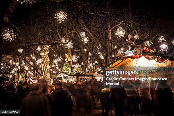 crowds of people at christmas market illuminated at night basel, switzerland - basel switzerland stock pictures, royalty-free photos & images