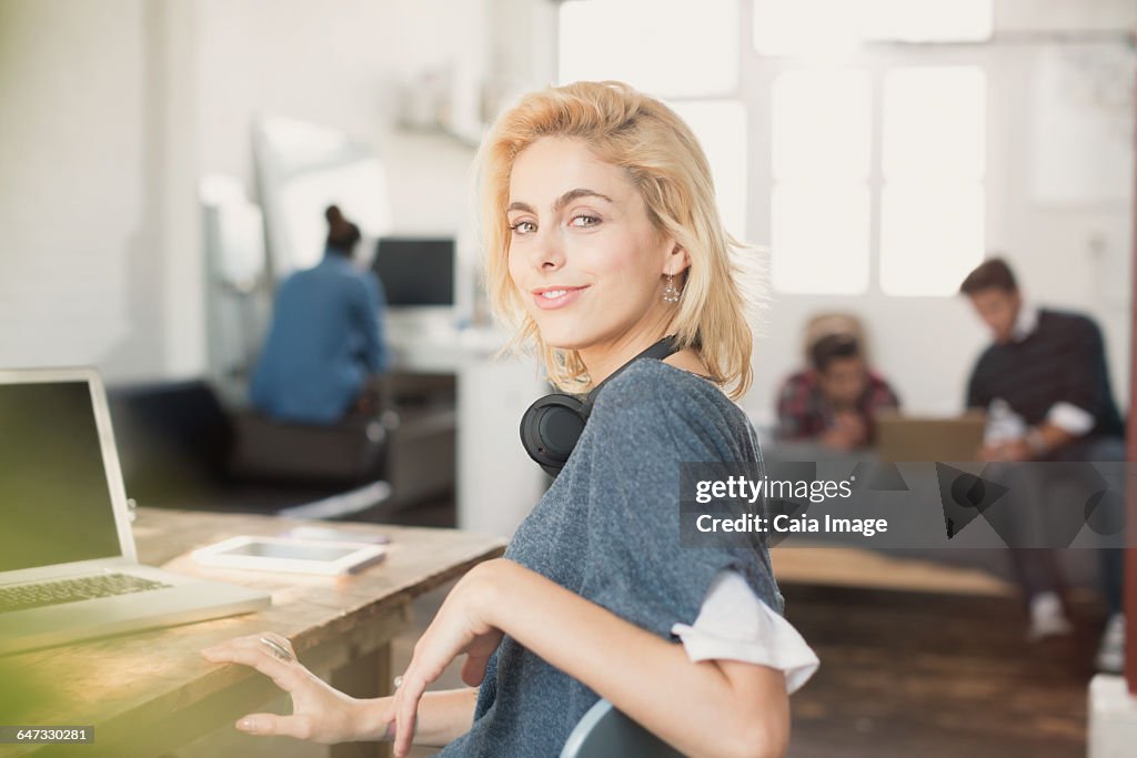 Portrait confident young female college student with headphones at laptop