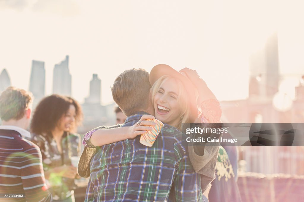 Enthusiastic young woman hugging man at rooftop party