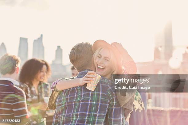 enthusiastic young woman hugging man at rooftop party - rooftop deck stock pictures, royalty-free photos & images