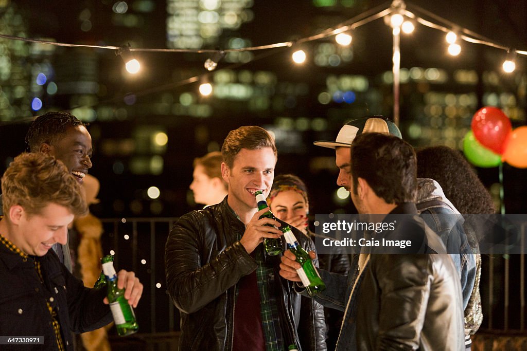 Young men drinking beer at rooftop party
