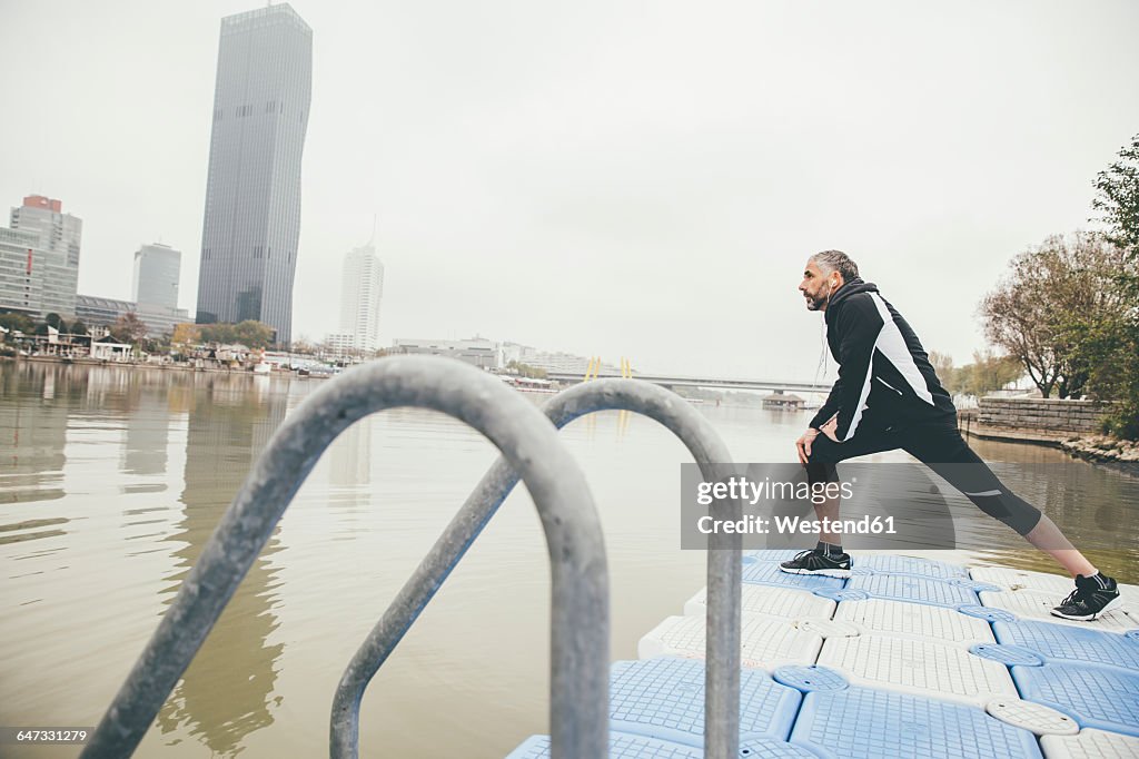 Austria, Vienna, jogger doing stretching exercise on Danube Island