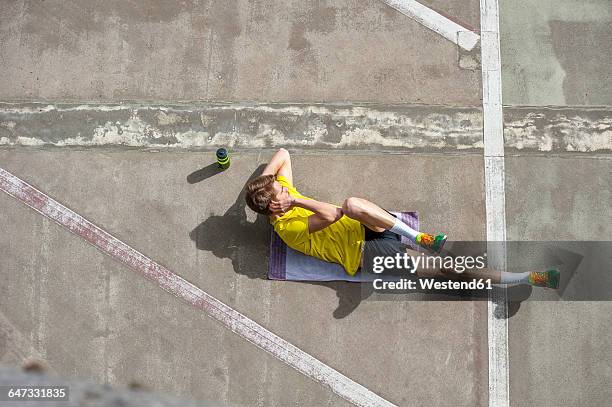 young sporty man doing situps on concrete floor - bodyweight training stock pictures, royalty-free photos & images