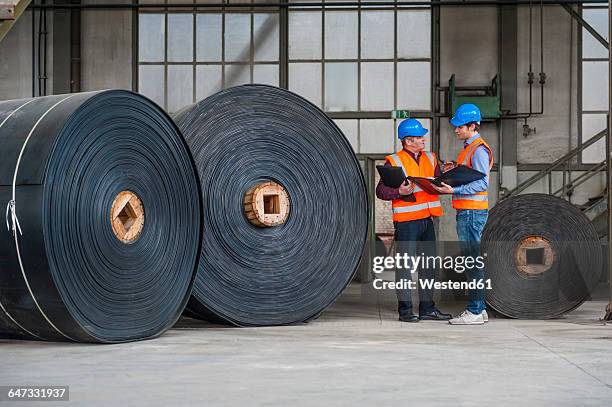 two men with documents in factory hall with rolls of rubbe - rubber material stock pictures, royalty-free photos & images