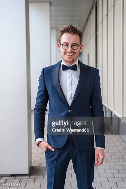 portrait of winking young man wearing suit and bow tie - 蝶ネクタイ ストックフォトと画像