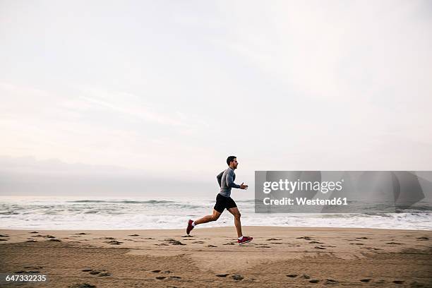 young man running on the beach - man running foto e immagini stock