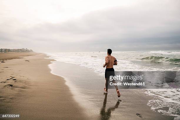 young man running on the beach - semi dress fotografías e imágenes de stock