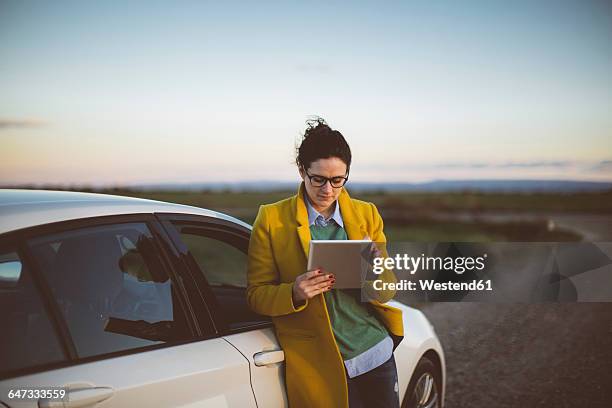 woman using digital tablet at car - auto tablet stockfoto's en -beelden