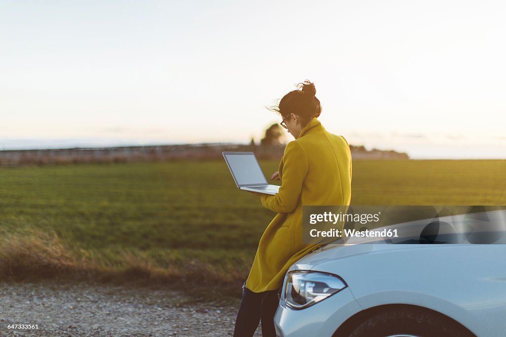 Woman using laptop at car