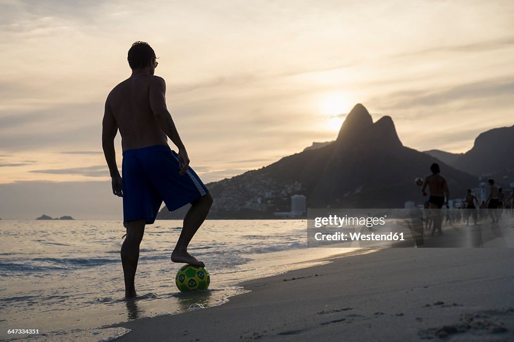 Brazil, Rio De Janeiro, man standing with ball on Ipanema beach