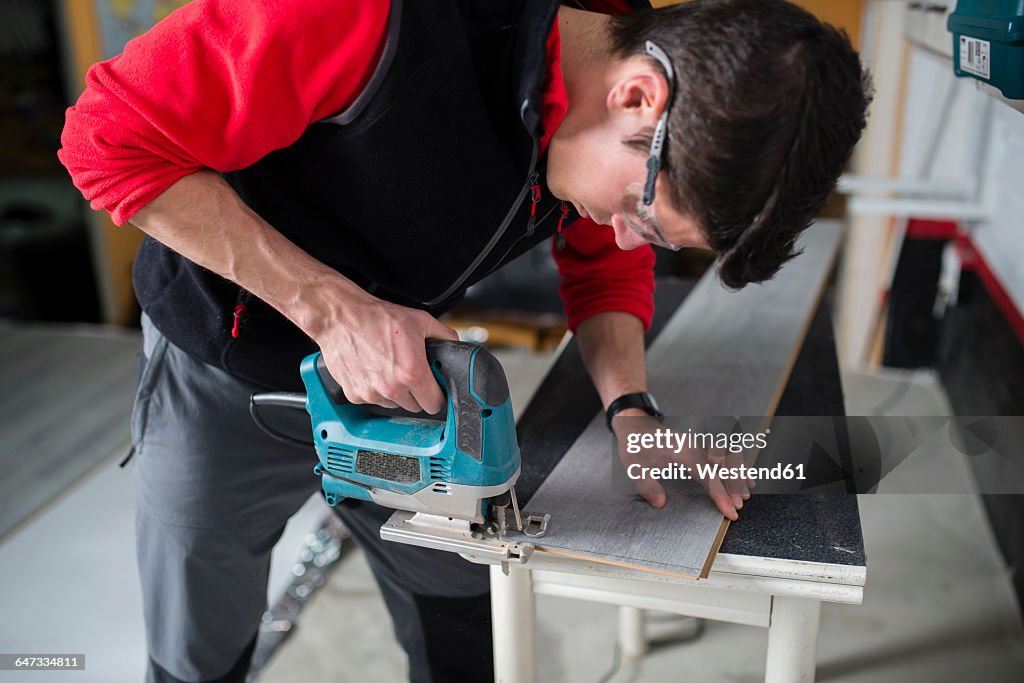 Man cutting laminate floor pieces with a jigsaw