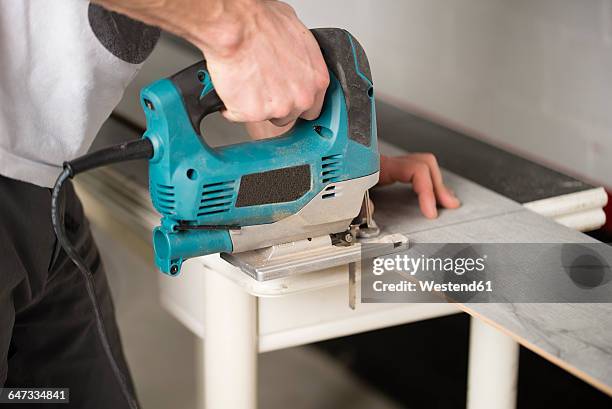 man cutting laminate floor pieces with a jigsaw - pavimento-in-laminato foto e immagini stock