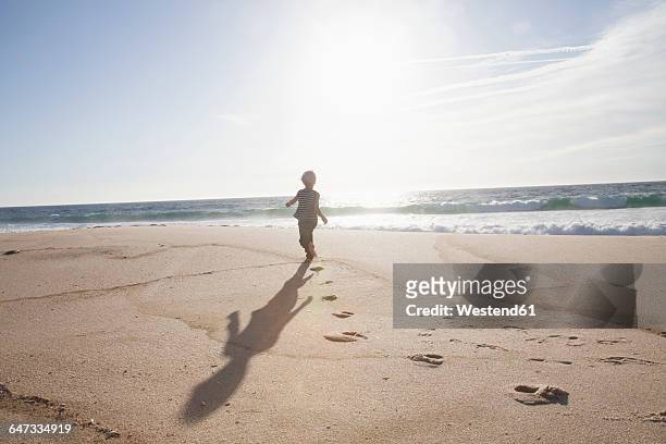 back view of boy running on the beach at twilight - beach boys stock pictures, royalty-free photos & images
