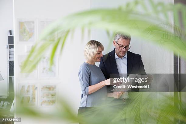 businessman and woman working together in office discussing documents - dedicación fotografías e imágenes de stock