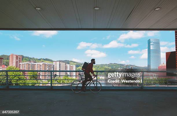 spain, bilbao, man riding racing cycle on a bridge - biscaglia foto e immagini stock