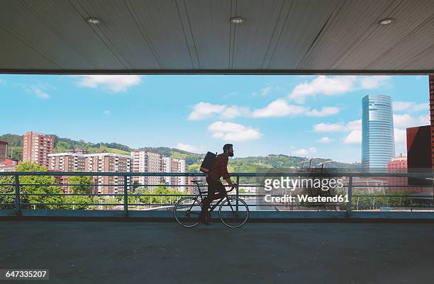 spain, bilbao, man riding racing cycle on a bridge - bilbao stock pictures, royalty-free photos & images