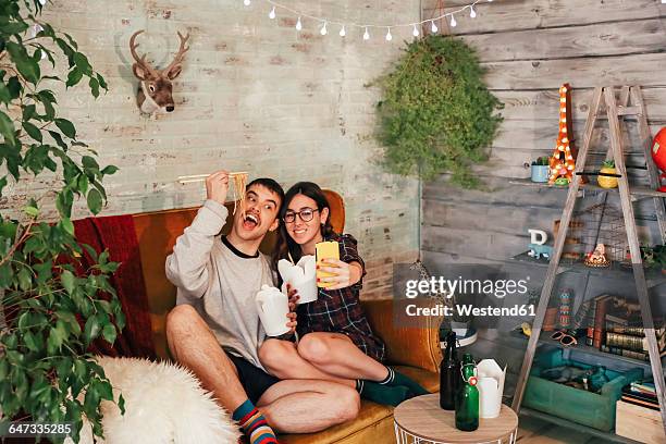 young couple eating chinese take-away food taking a selfie - chinese takeout stock pictures, royalty-free photos & images