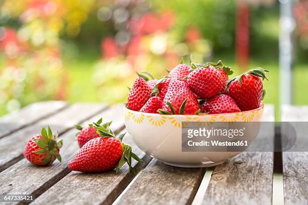 bowl of strawberries on wooden garden table - strawberry stock pictures, royalty-free photos & images