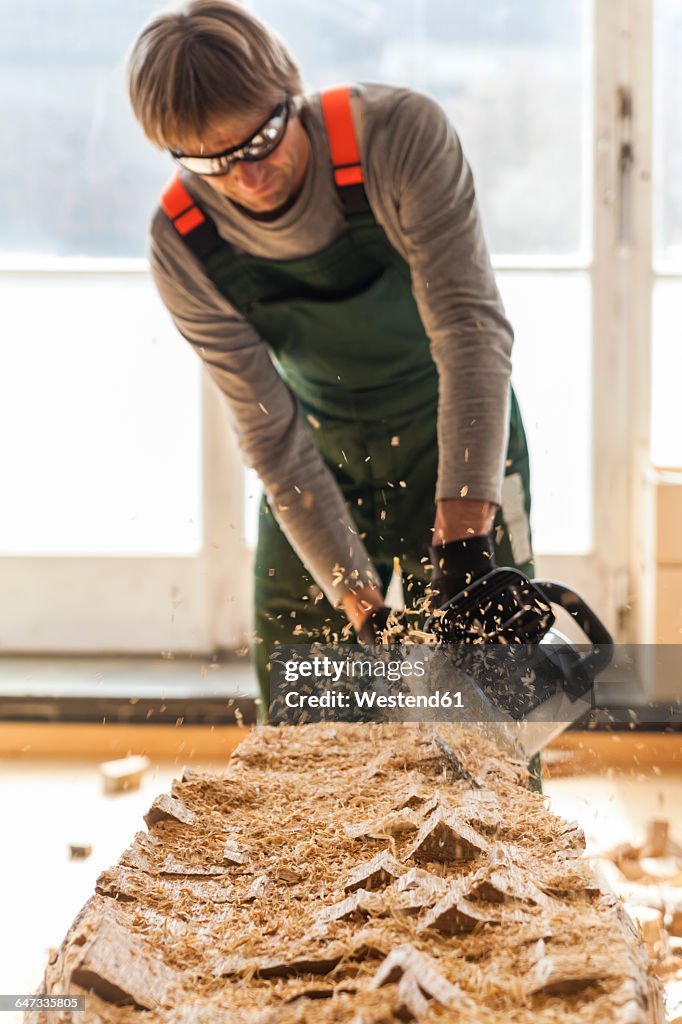 Wood carver in workshopworking on wood for a sculpture with a chainsaw