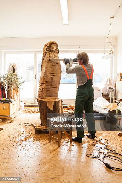 wood carver in workshop working on sculpture with chainsaw - sculptor stock pictures, royalty-free photos & images
