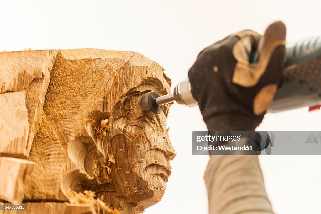 Wood carver in workshop working on sculpture with milling machine