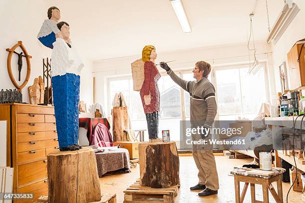 wood carver in workshop painting his sculpture - dießen stock-fotos und bilder