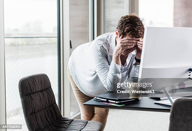 businesswoman leaning on desk with head in hands - lean head on hands photos et images de collection