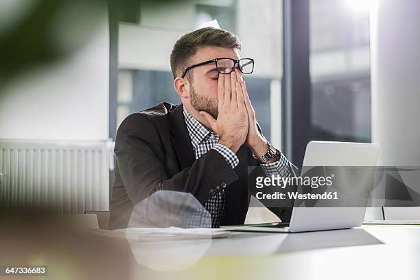 exhausted young man with laptop in office - frustración fotografías e imágenes de stock