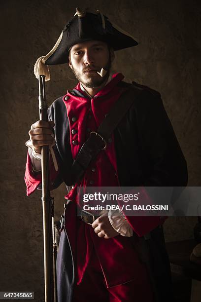 Soldier of the Saluzzo regiment with tricorn, pipe and muzzle-loading flint-lock rifle Kingdom of Sardinia army, 18th century. Historical reenactment.