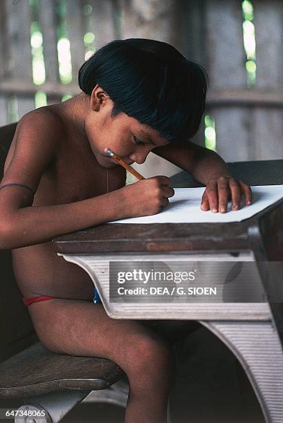 Yanomami child writing on a school bench, The Amazon rainforest, Venezuela.